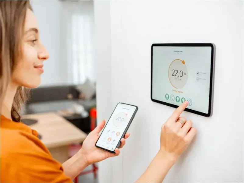 Smart Heating Controls – Peaks Electrical Bath Customer using a smart heating control system on a wall and mobile phone installed by Peaks Electrical in Bath.