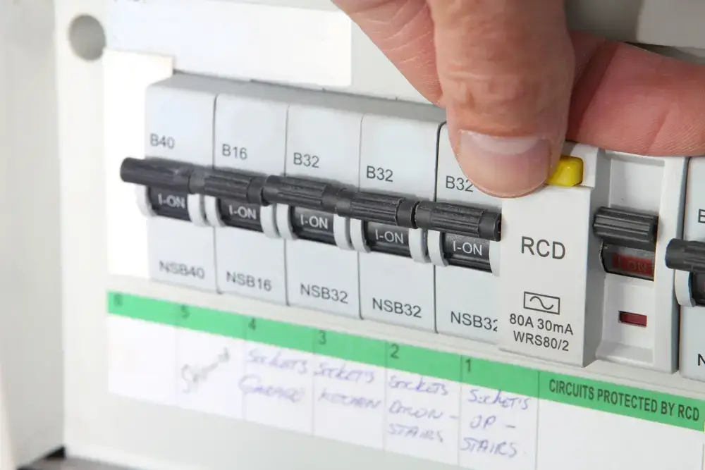 Modern fuse board with labelled circuit breakers and RCD switch being tested